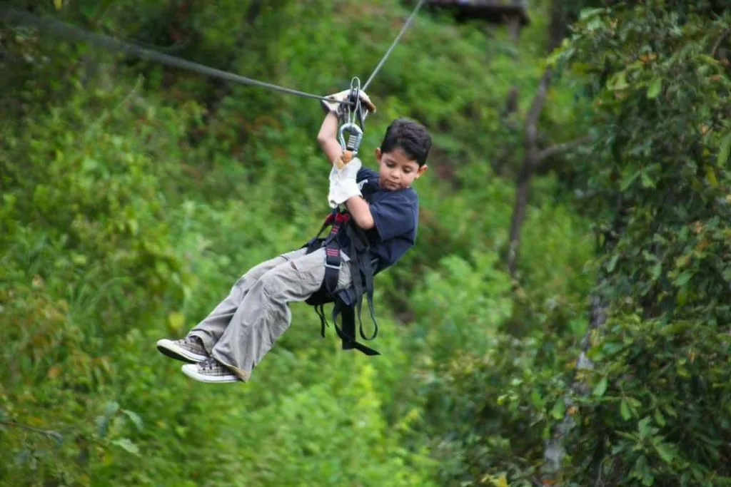 Grupo de amigos con cascos y arneses sonriendo en plataforma del canopy